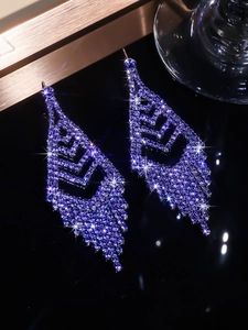 Detailed view of long blue rhinestone tassel earrings on a sleek black background