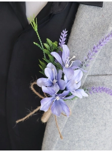 Dettaglio di un fiore all'occhiello con gigli viola e lavanda su abito grigio