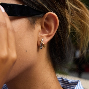 Two-tone mixed metal crisscross stud earrings in gold and silver finish on model