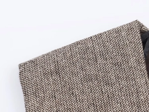 Close-up of tan and beige tweed wool texture and stitching on the dress shoulder
