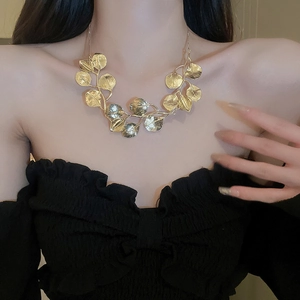 Close-up of golden leaf necklace worn on model neck highlighting sleek metallic texture