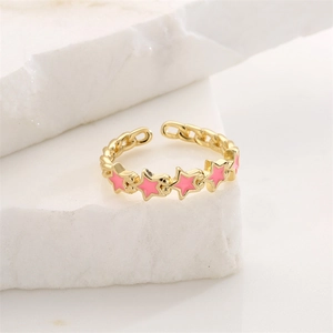 Detail of gold chain ring with five pink enamel stars on a white stone background
