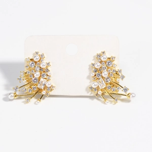 Detail showing golden branch-shaped stud earrings with embedded pearls and rhinestones