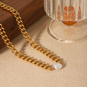 Gold Cuban chain necklace for women featuring a round pearl pendant on a rustic display