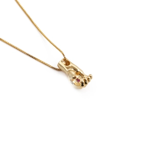 Gold plated palm necklace with evil eye pendant and red ruby gemstone on white background