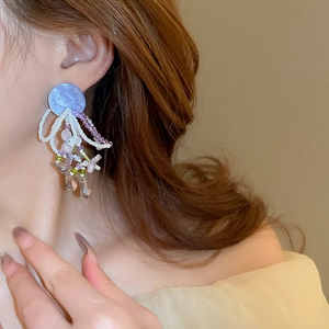 Gros plan détaillé de boucles d'oreilles à pompons perlés avec acrylique violet et cristaux