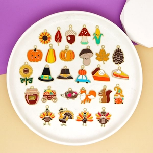 Detailed collection of 24 colorful enamel Thanksgiving charms on a white display plate