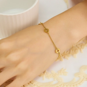 Detail of gold chain bracelet with Roman numeral rings worn on a wrist in elegant setting