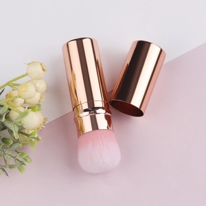 Detailed close-up of rose gold retractable makeup brush with pink gradient soft bristles