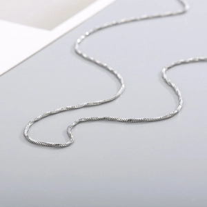 Macro detail of high-polish silver stainless steel snake chain showing textured link weave