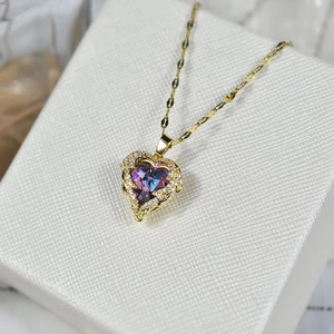 Nahaufnahme von goldenem Herzanhänger mit blau-violettem Kristall und kleinen Diamanten