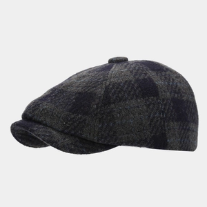 Detail view of dark grey plaid newsboy cap showing wool blend texture and button top