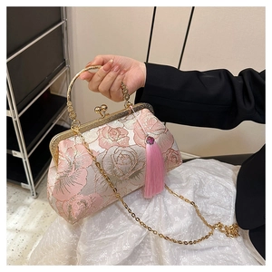 Detail of pink embroidered rose pattern and long tassel on retro shell handbag