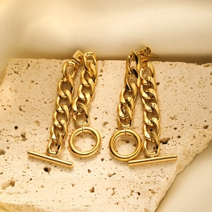 Detailed close-up of 18K gold-plated OT buckle chain earrings on a beige stone block