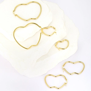 Detailed macro view of multiple sizes of gold heart hoop earrings on stone display