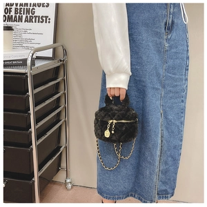 Detail of black faux fur mini bag with gold chain strap and camellia flower pendant