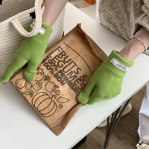 Detail of green knitted touchscreen gloves featuring white woven wrist labels