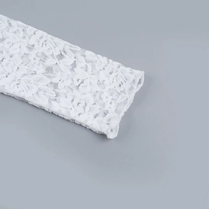 Vue détaillée de la texture de dentelle florale blanche sur le poignet de la manche