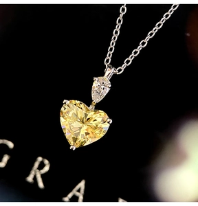 Macro shot of heart-shaped yellow moissanite pendant on a silver box chain necklace