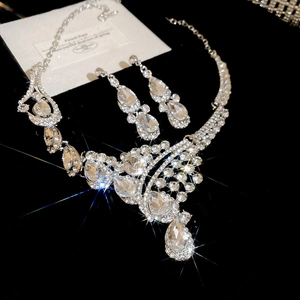 Macro shot of silver-toned drop necklace and earrings set with sparkling crystals
