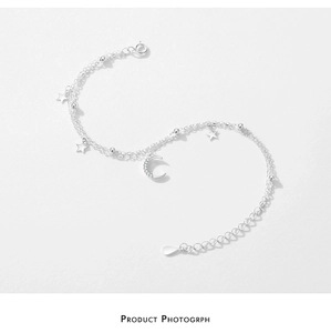 Macro detail of silver S925 double-layer bracelet with star and crescent moon pendants