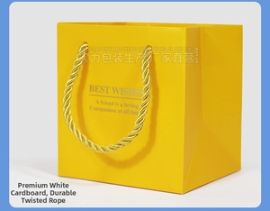 Yellow gift paper bag with golden braided rope handles and silver foil stamped text