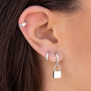 Détail du pendentif cadenas en argent et des créoles sur l'oreille au style punk chic