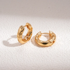Macro detail of golden geometric hoop earrings featuring unique irregular wrinkled texture