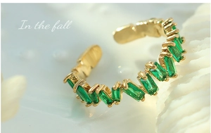 Macro detail of adjustable gold-plated ring with rectangular emerald green zircons