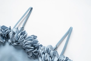 Détail de fleurs 3D faites à la main sur un maillot de bain en satin bleu clair