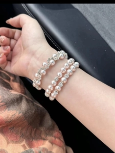 Detail view of layered pearl and rhinestone bracelets with elegant pink luster on the wrist