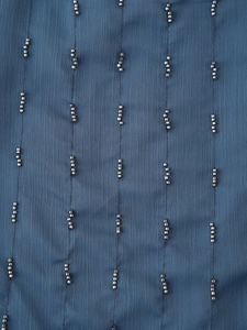 Detailed macro view of navy blue chiffon fabric with vertical silver bead embellishments