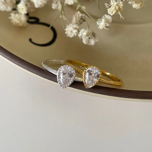Minimalist 925 silver rings with teardrop zircon on a ceramic plate with dried flowers