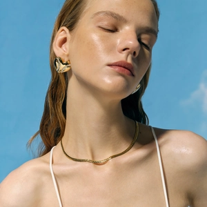 Close-up of golden heart earrings with pavé diamonds and matching necklace on a model