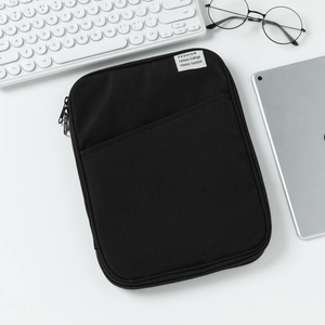 Detail of black padded iPad sleeve with front pocket and zipper on minimalist desk