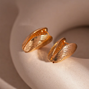 Detail of golden shell earrings with textured radial patterns and a polished finish