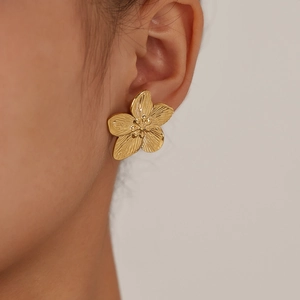 Macro shot of French vintage gold flower stud earrings featuring five-petal textured design