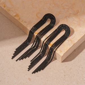 Detail shot of black rhinestone fringe drop earrings on a warm marble surface