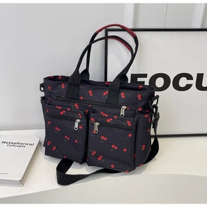 Side view of black canvas tote bag with cherry print and adjustable shoulder straps