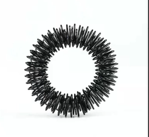 Close-up of black metal spiral spring finger massage ring for stress relief
