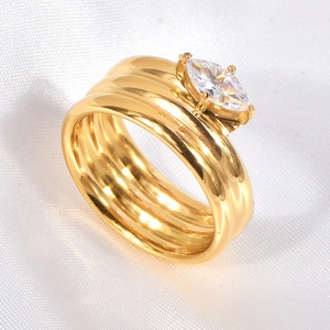 Detail of multilayer gold ring with marquise-cut zircon on white silk background