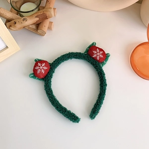 Detail of green plush Christmas headband with red snowflake balls on a festive table