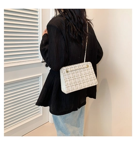 Detail of tweed crossbody bag with golden chain strap on a model's shoulder