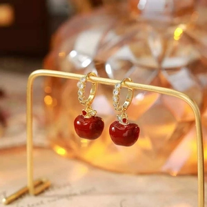 Elegant gold-plated red apple earrings with zircon stones on a gold jewelry stand