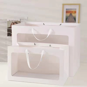 Detailed view of white paper gift bags with PVC windows and elegant satin handles