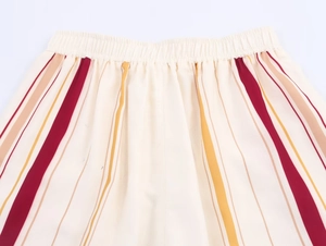 Détail de la taille élastique d'un pantalon rayé aux motifs verticaux rouges et oranges