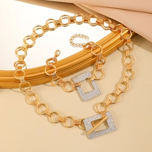 Macro della collana a catena intrecciata dorata con ciondolo quadrato di strass