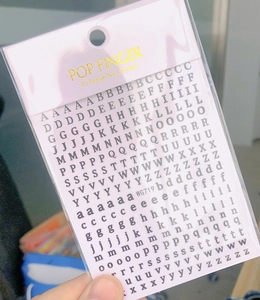 Close-up of black 3D alphabet nail stickers in transparent packaging, model WG719