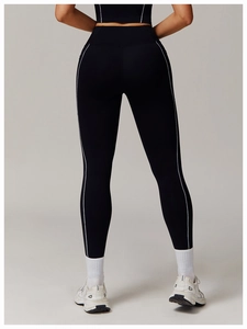 Detalle de pantalones de yoga negros de talle alto con rayas blancas laterales y ajuste ceñido