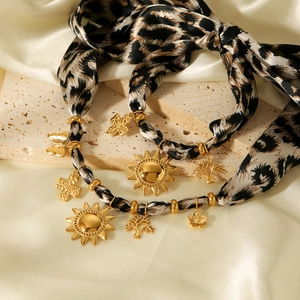 Macro detail of leopard print ribbon necklace with assorted gold sun and butterfly charms
